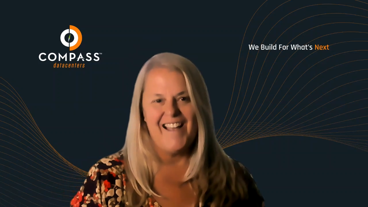 The image shows a smiling person in front of a dark background with the logo "COMPASS datacenters" and the slogan "We Build For What’s Next."